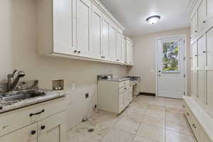 Laundry area featuring cabinet space, light tile patterned floors, electric dryer hookup, and washer hookup