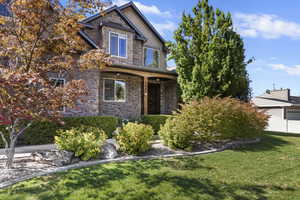 Craftsman house featuring stone siding and a front yard
