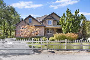 View of front of house featuring stucco siding, a fenced front yard, stone siding, a porch, and a gate