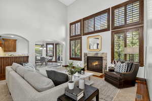 Living area featuring a chandelier, a fireplace, a towering ceiling, wood finished floors, and arched walkways