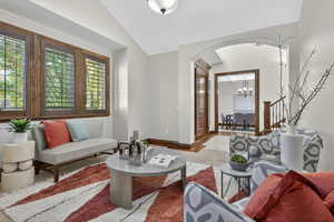 Living area featuring a chandelier, lofted ceiling, arched walkways, and tile patterned floors