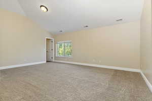 Unfurnished room featuring light carpet and lofted ceiling