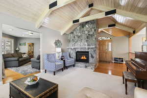 Vaulted ceilings with exposed beams and a stone fireplace anchor this spacious living room