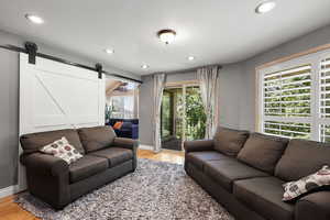 Versatile living room with barn door detail and direct walk-out to a private balcony