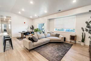 Living area with vaulted ceiling, light wood-type flooring, and recessed lighting