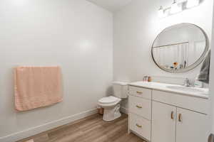 Full bath with vanity, light wood-style floors, and curtained shower