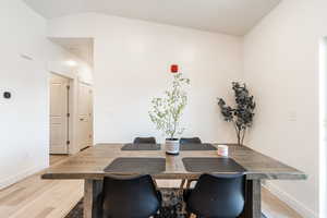 Dining room with light wood-style flooring and lofted ceiling