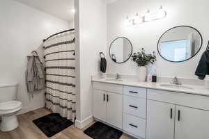 Full bathroom featuring double vanity, light wood-type flooring, and curtained shower