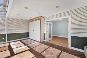 Empty room featuring wooden walls, recessed lighting, tile patterned flooring, and french doors