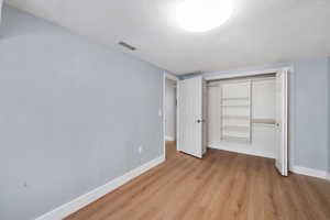 Unfurnished bedroom with light wood-style floors and a closet