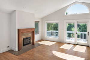 Unfurnished living room with vaulted ceiling, light wood-style floors, a fireplace, and recessed lighting