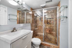 Bathroom with vanity, a stall shower, and a textured ceiling