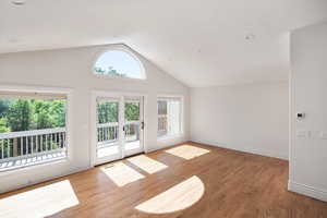 Doorway with lofted ceiling, wood finished floors, and recessed lighting