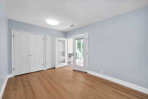 Unfurnished bedroom with two closets, access to outside, and light wood finished floors