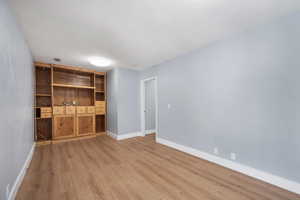 Unfurnished living room with light wood-style flooring and baseboards