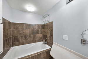 Full bath featuring a textured ceiling and a bath