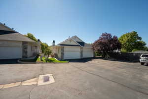View of side of property featuring driveway, stone siding, and a chimney