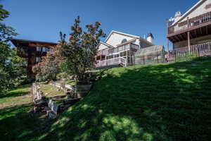 View of grassy yard featuring a vegetable garden and a deck