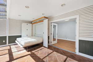 Bedroom featuring wooden walls, a closet, recessed lighting, and tile patterned floors