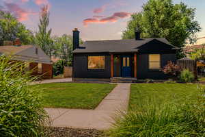 View of front facade featuring a chimney, brick siding, and roof with shingles