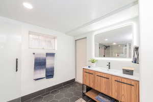 Bathroom featuring vanity, dark tile patterned flooring, a shower, a textured ceiling, and recessed lighting
