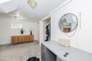 Office space with a textured ceiling and light colored carpet