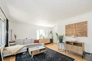 Living room with crown molding and wood finished floors