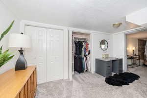 Bedroom featuring light colored carpet, a textured ceiling, and two closets