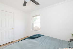 Bedroom with crown molding, wood finished floors, and ceiling fan