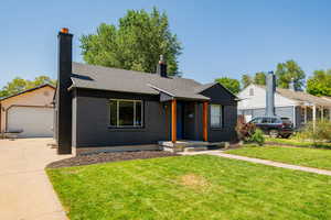 Ranch-style house featuring a chimney, a front yard, brick siding, and a shingled roof