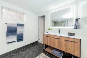 Full bathroom featuring vanity, tiled shower, and dark tile patterned flooring
