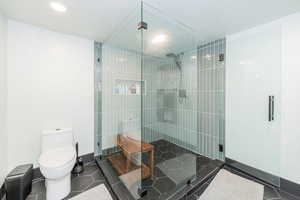 Bathroom featuring walk in shower, a textured ceiling, and dark tile patterned flooring