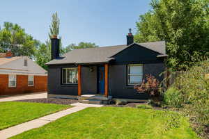 Ranch-style house with a front lawn, a chimney, brick siding, a porch, and a shingled roof