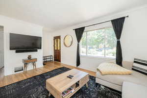 Living area with wood finished floors and ornamental molding
