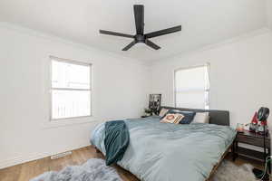 Bedroom with hardwood / wood-style flooring, ornamental molding, a ceiling fan, and a textured ceiling