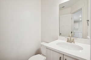 Half bathroom featuring vanity and toilet