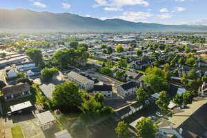 Aerial view of property and surrounding area featuring mountains and nearby suburban area