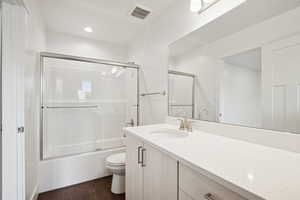 Full bath featuring bath / shower combo with glass door, vanity, dark wood-type flooring, and recessed lighting