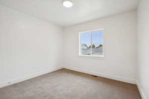 Carpeted spare room featuring baseboards