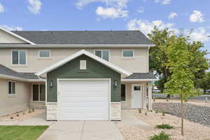 Traditional-style home with stone siding, stucco siding, a shingled roof, and a garage