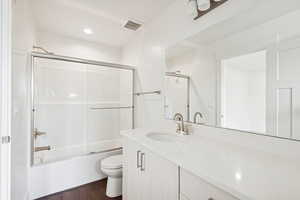 Bathroom featuring enclosed tub / shower combo, vanity, dark wood finished floors, and recessed lighting