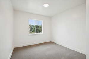 Carpeted spare room featuring baseboards