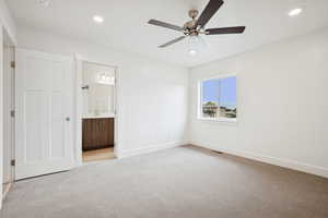 Unfurnished bedroom featuring light colored carpet, recessed lighting, ceiling fan, and ensuite bath