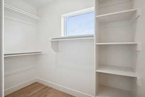 Walk in closet with light wood finished floors