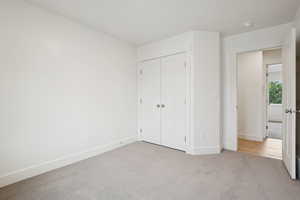Unfurnished bedroom featuring light carpet and a closet