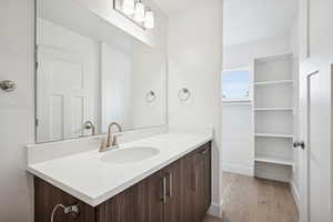 Bathroom with vanity, light wood finished floors, and a spacious closet