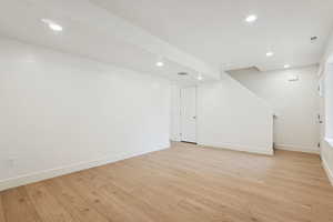 Finished below grade area with light wood-style flooring and recessed lighting