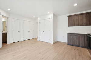 Bar with dark brown cabinets, light wood-type flooring, recessed lighting, black range oven, and modern cabinets