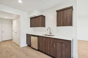 Kitchen featuring dark brown cabinets, recessed lighting, light wood-style flooring, modern cabinets, and dishwasher