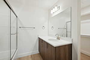 Full bathroom featuring light wood-style floors, vanity, and combined bath / shower with glass door